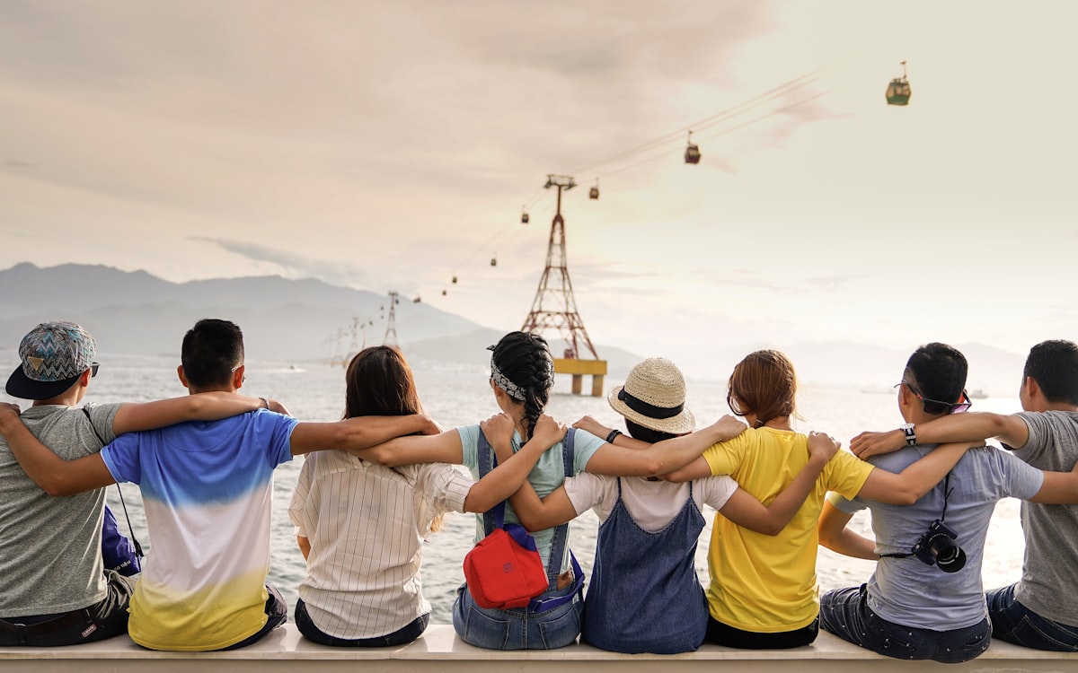A line of friends sitting arm in arm looking out over the water